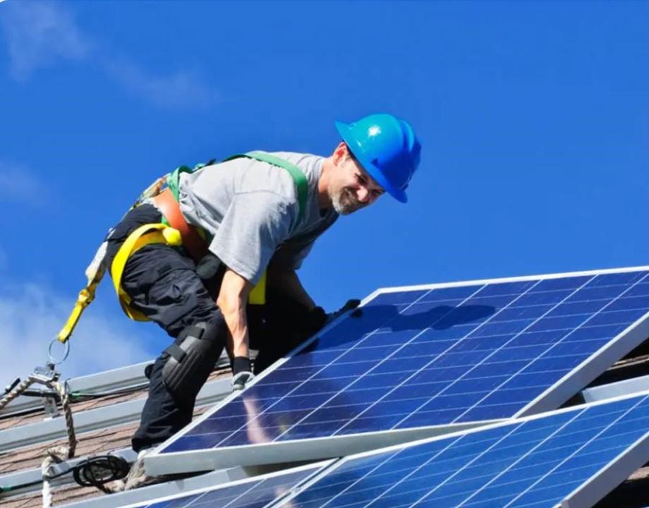Man op het dak bezig met zonnepanelen leggen