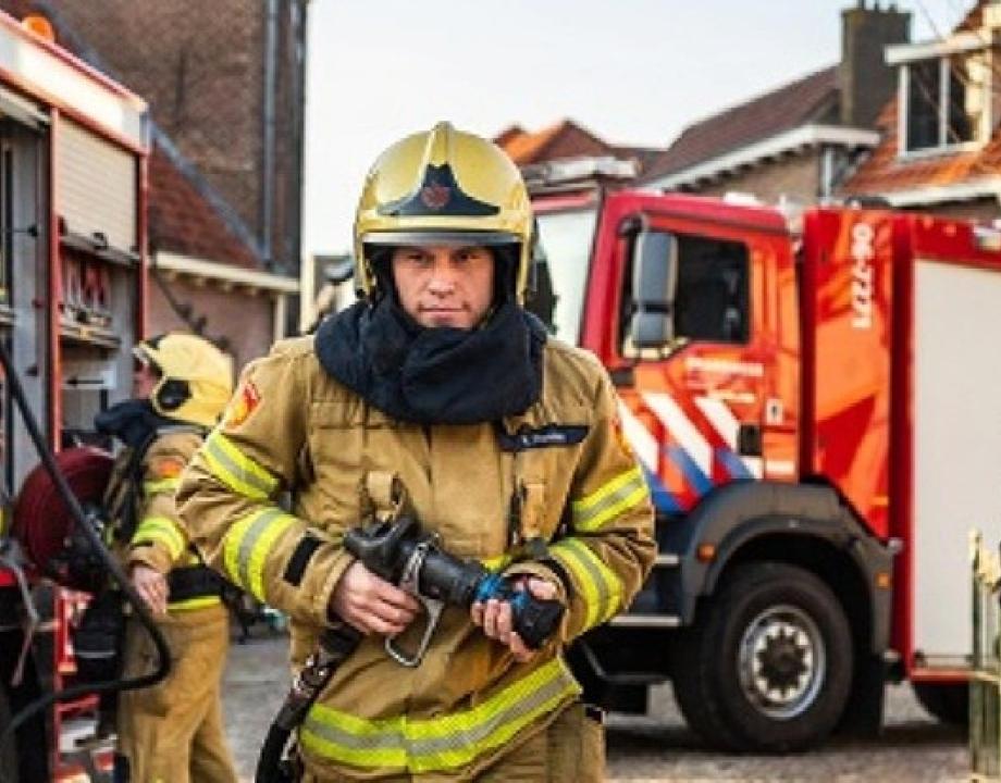 Brandweerman en blusvoertuigen tussen huizen