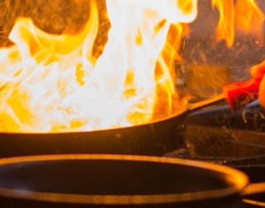 Koekenpan staat in de brand boven een fornuis