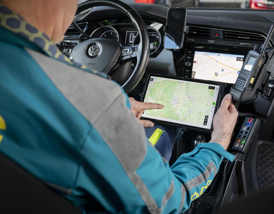 Een GHOR medewerker zit in een auto en kijkt op een scherm met een plattegrond